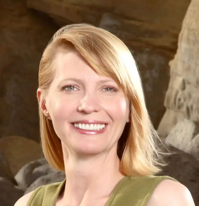 A woman with blonde hair and green dress smiling.