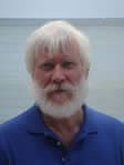 A man with white hair and beard wearing blue shirt.