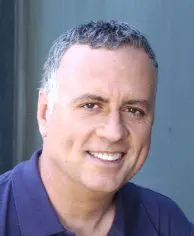 A man with grey hair and a blue shirt.