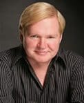 A man with blonde hair and wearing a black shirt.