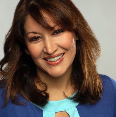 A woman with long hair and blue shirt smiling.