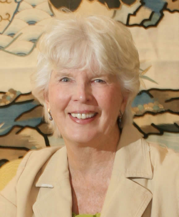 A woman with white hair is smiling for the camera.