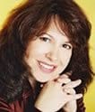 A woman with brown hair and a red shirt is smiling.